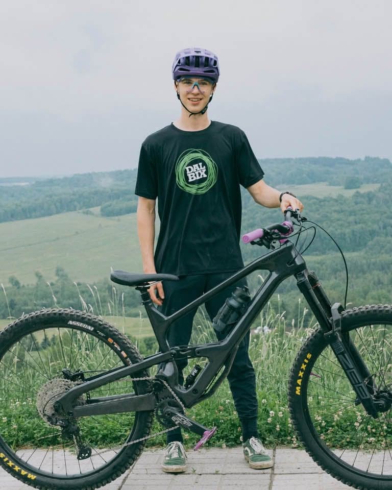 Zac debout à côté de son vélo d'enduro dans un champ